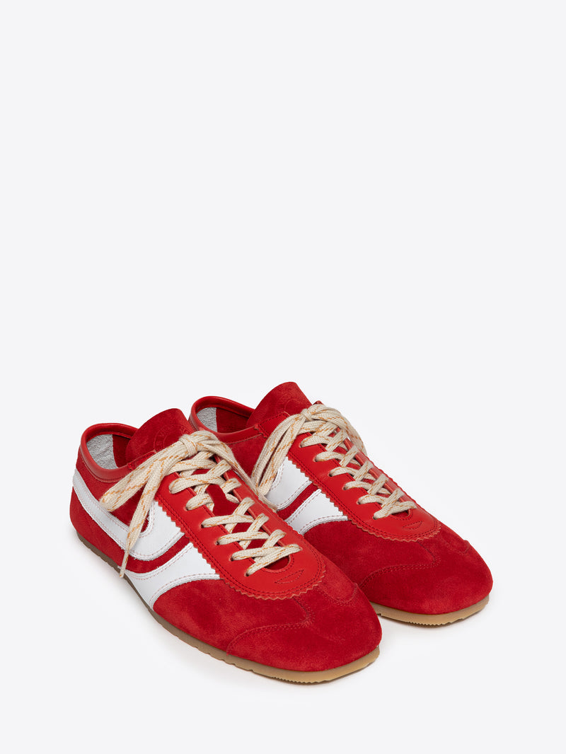 Pair of red suede sneakers with white stripes and cream colored laces on a white background
