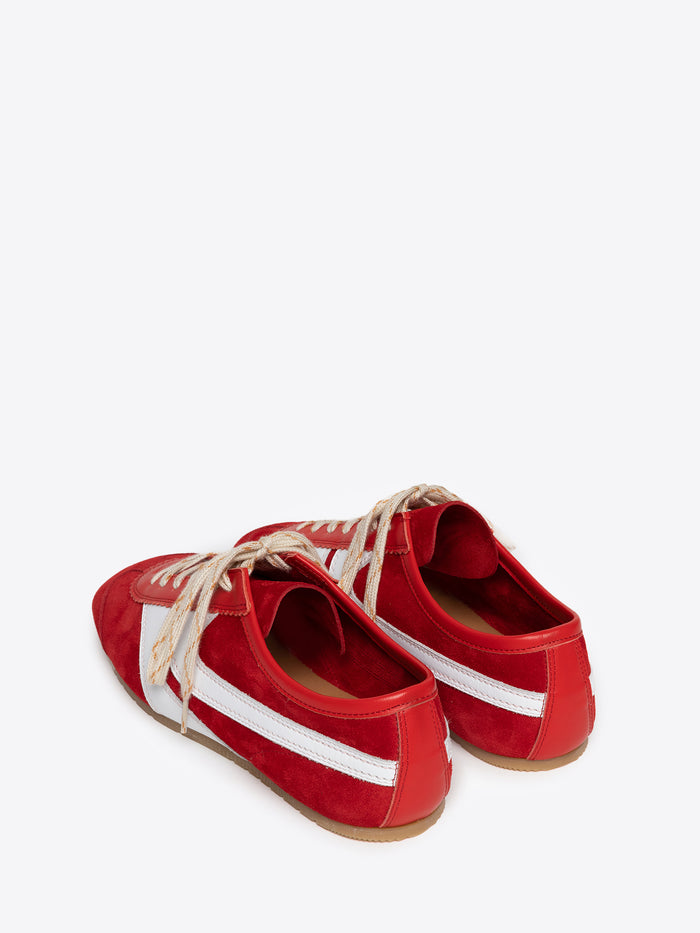 Backside of a pair of red suede sneakers with white stripes and cream colored laces on a white background
