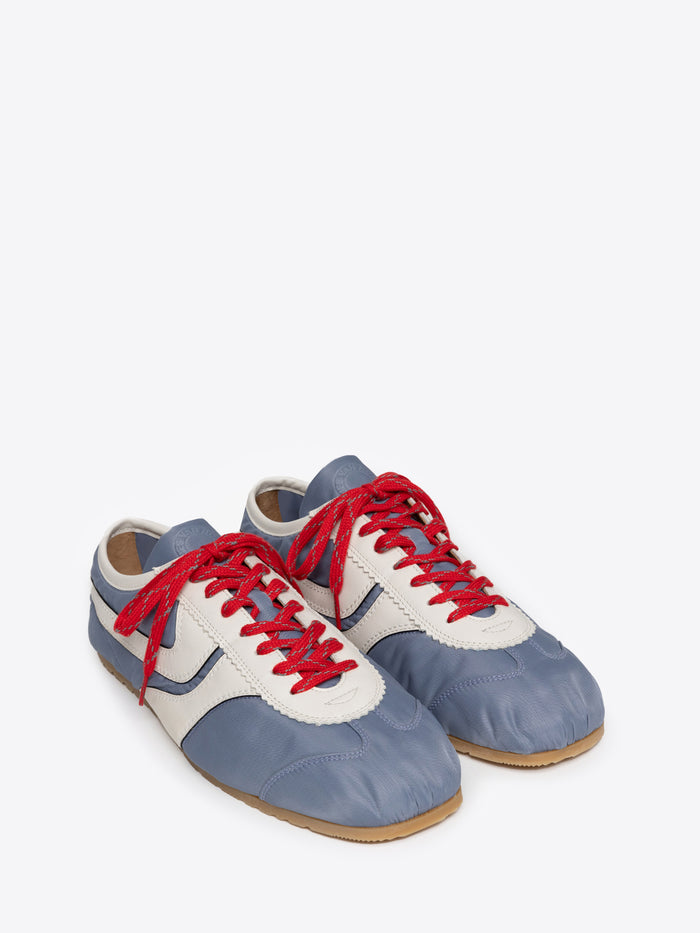 Pair of blue and white suede sneakers with red laces on a white background