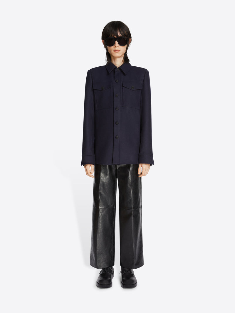 Person wearing a dark blue jacket and black leather pants on a white background