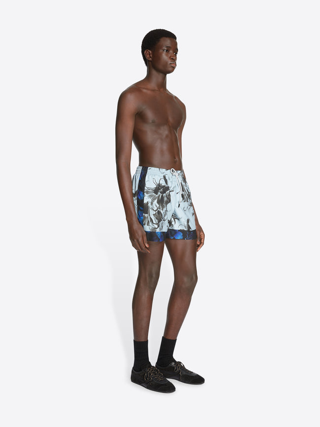 Model wearing mint colored, printed swim shorts on a white background