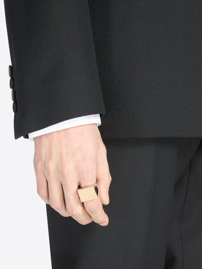 Person wearing a black suit with a handmade gold square signet ring in precious plated eco brass.
