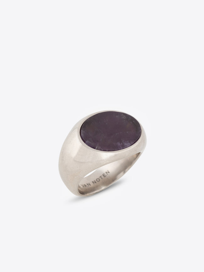 Silver ring with a flat dark purple stone on a white background