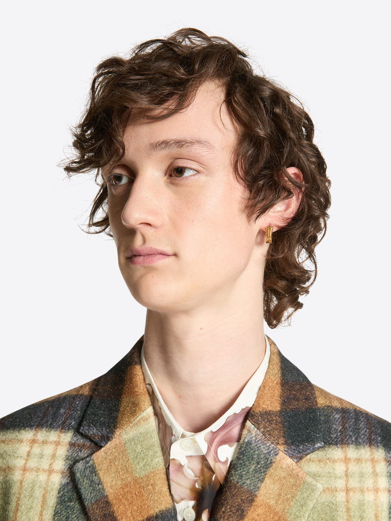 Person wearing a mat gold clasp earring on a white background