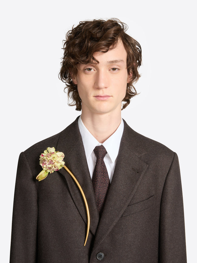 Person wearing a long curved mat gold brooch on a white background