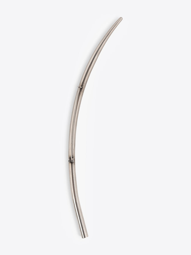 Long curved palladium brooch on a white background