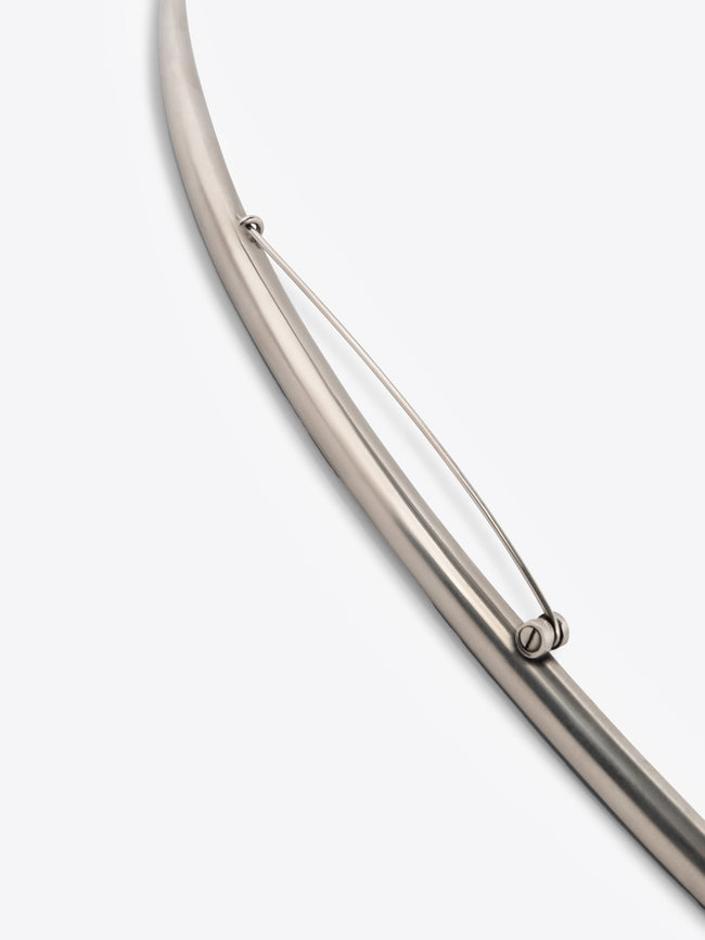 Long curved palladium brooch on a white background