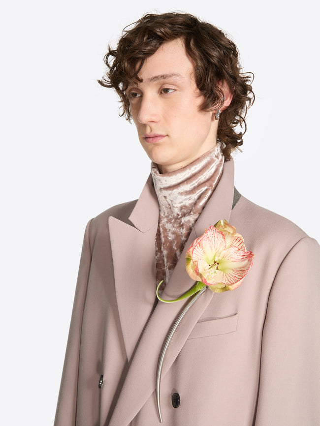 Person wearing a long curved palladium brooch on a white background