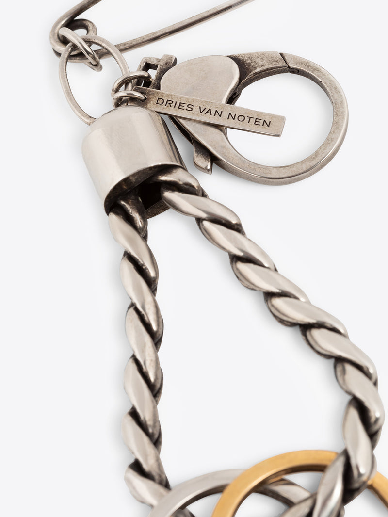 Close-up of a palladium keychain with a safety pin and two rings on a white background
