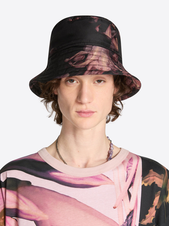 Person wearing a black floral bucket hat on a white background