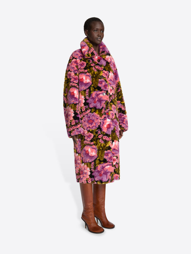 Model wearing a floral coat on a white background