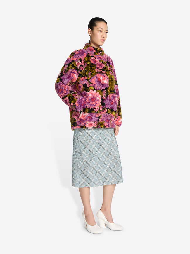 Person wearing a floral jacket and plaid skirt on a white background