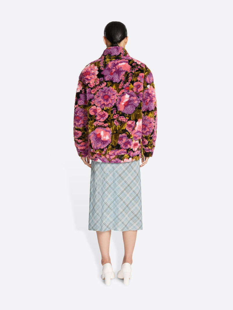 Person wearing a floral jacket and plaid skirt on a white background