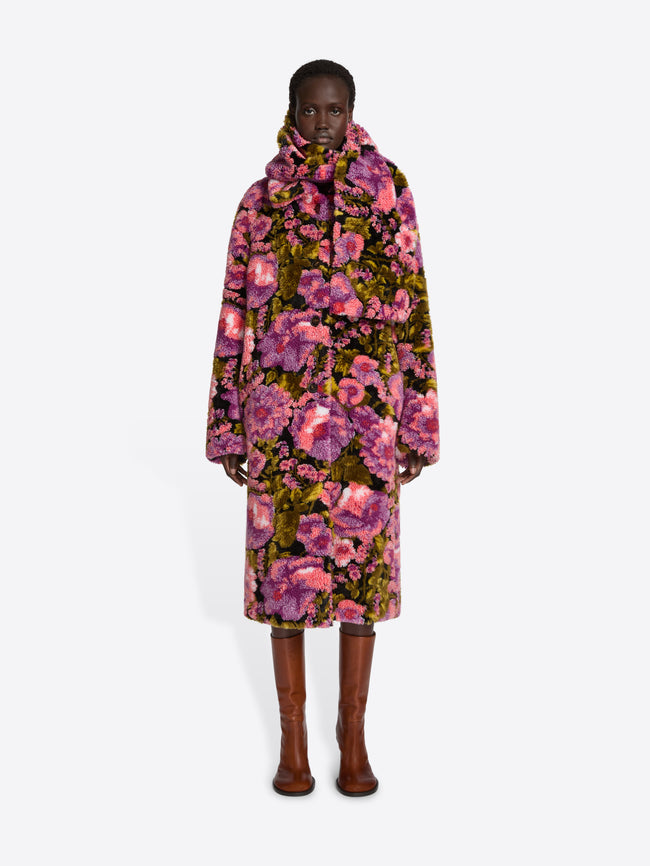 Model wearing a floral coat on a white background