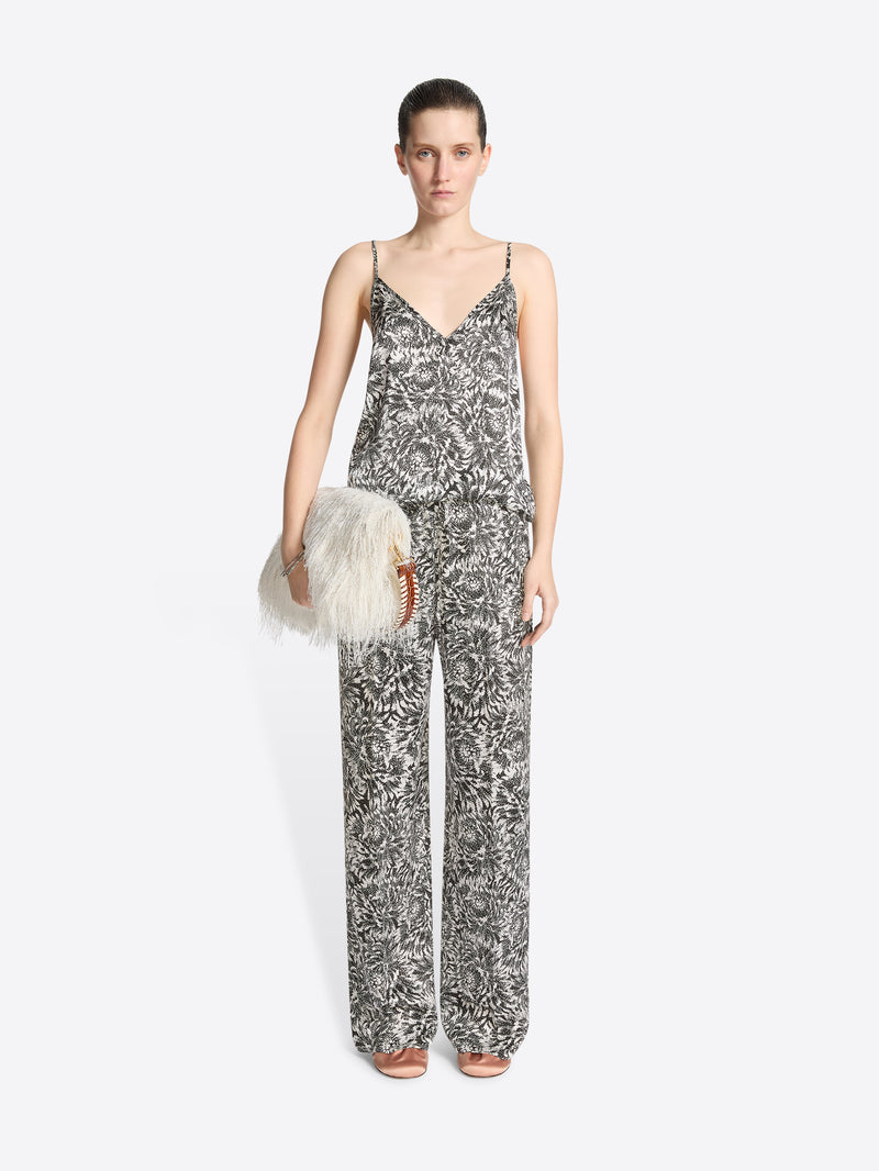 Woman wearing a patterned jumpsuit holding a fluffy white bag on a white background