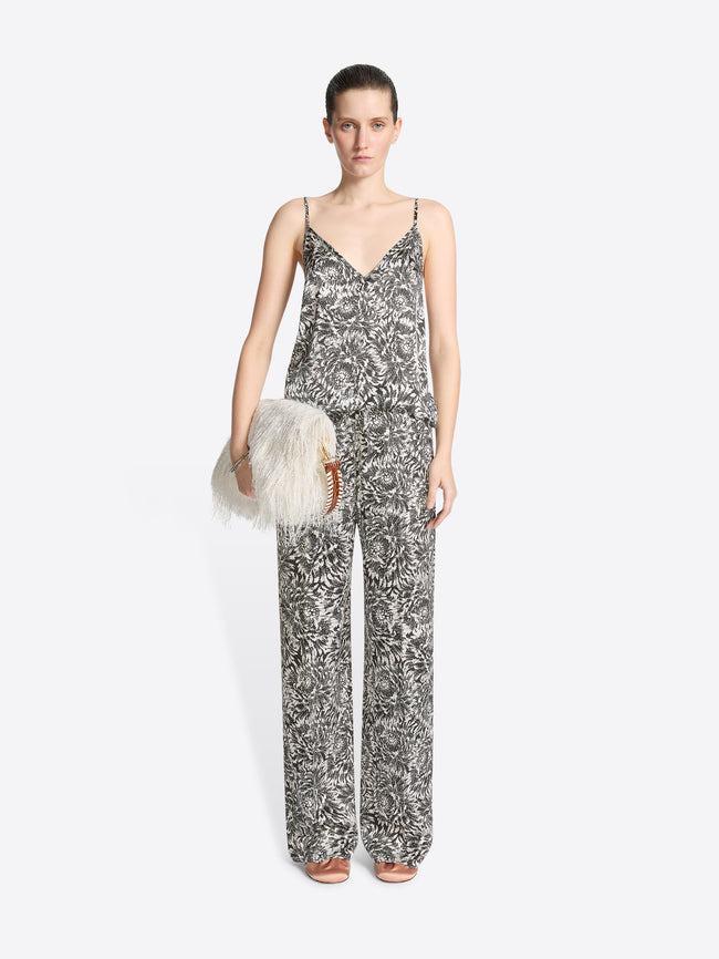 Woman wearing a patterned jumpsuit holding a fluffy white bag on a white background