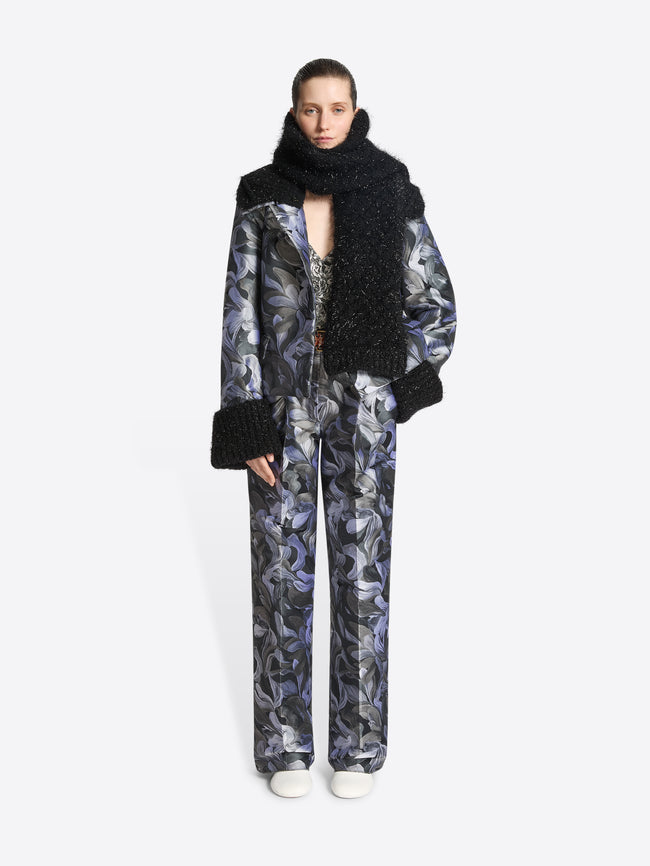 Person wearing a black coat with fur trim and a matching scarf, standing against a white background.