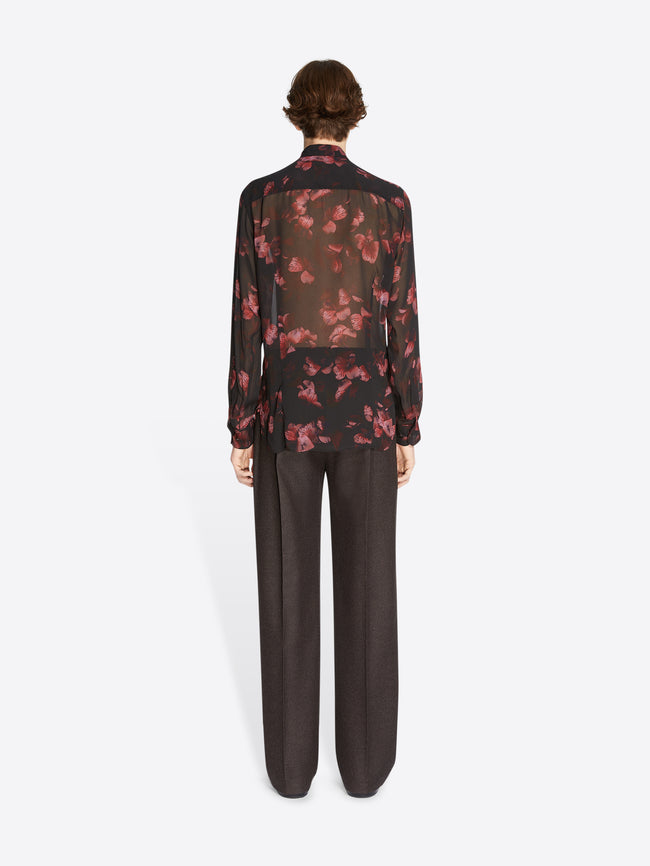 Person wearing a floral blouse and dark pants on a white background