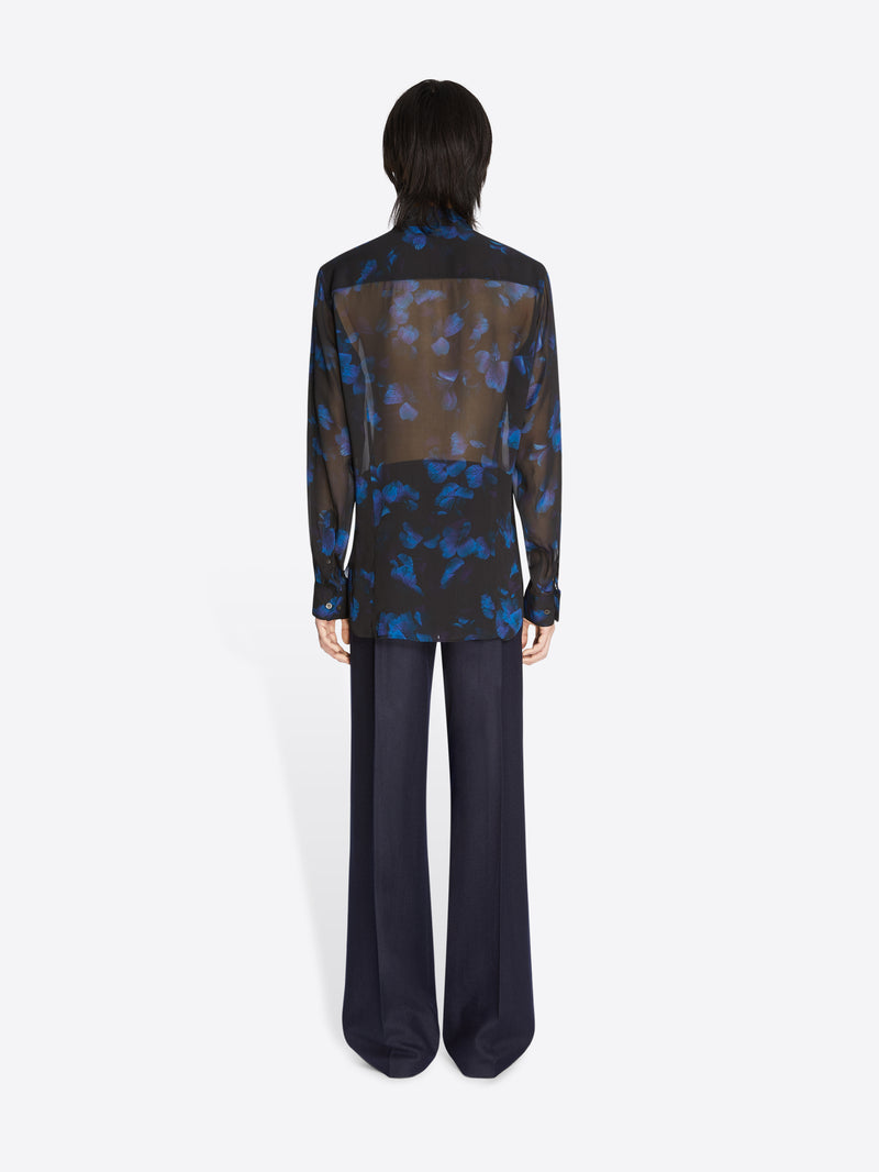 Person wearing a black and blue patterned blouse with wide-leg pants on a white background