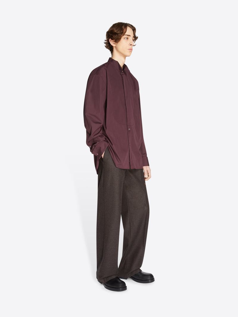 Model wearing a burgundy shirt and dark brown, floral embroidered wool pants on a white background