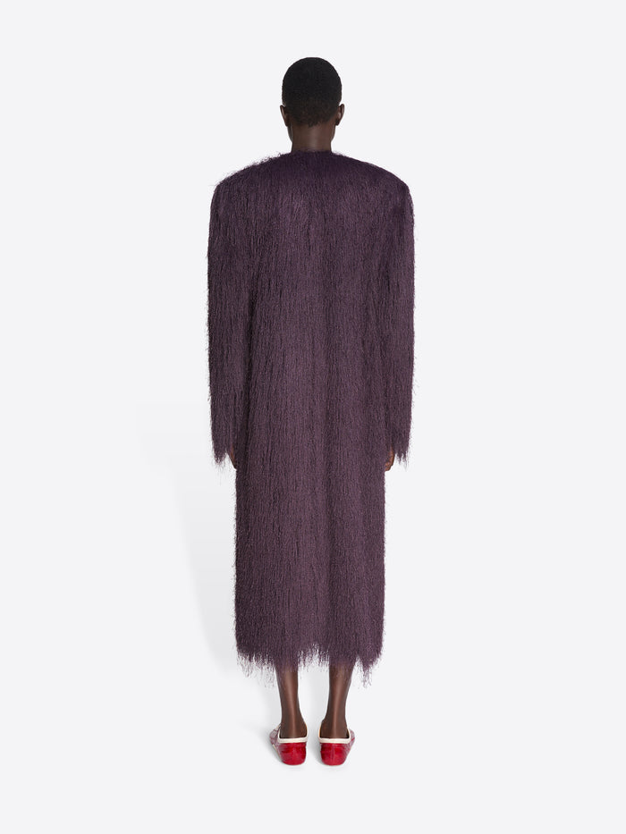 Person wearing a long, dark purple textured coat on a white background - Dries Van Noten