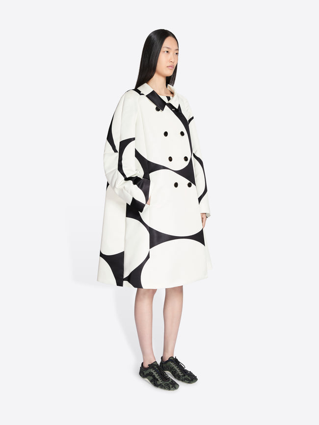Person wearing a black and white patterned coat on a white background - Dries Van Noten