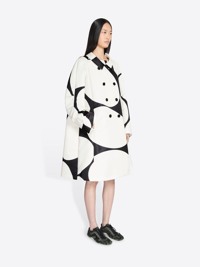 Person wearing a black and white patterned coat on a white background - Dries Van Noten