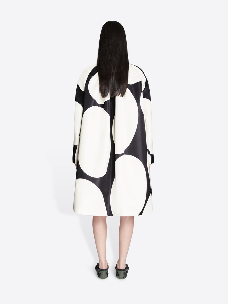 Person wearing a black and white patterned coat on a white background - Dries Van Noten