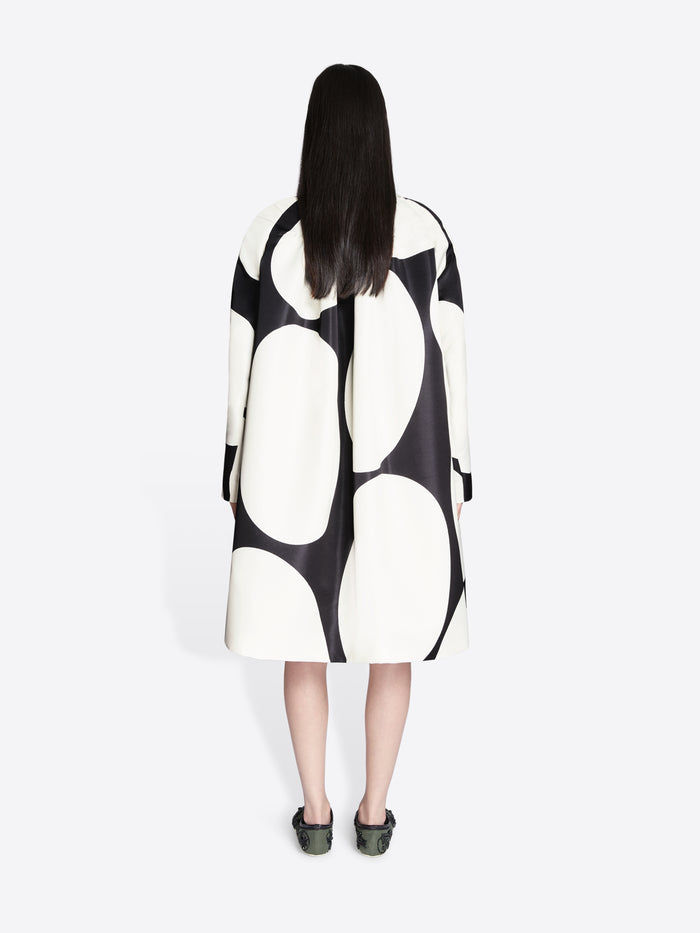 Person wearing a black and white patterned coat on a white background - Dries Van Noten