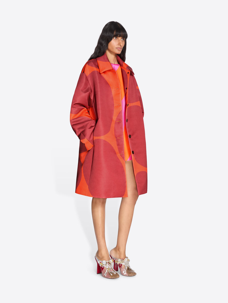 Woman wearing a red and orange patterned coat on a white background - Dries Van Noten