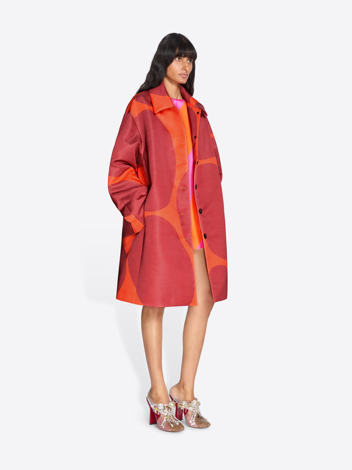 Woman wearing a red and orange patterned coat on a white background - Dries Van Noten