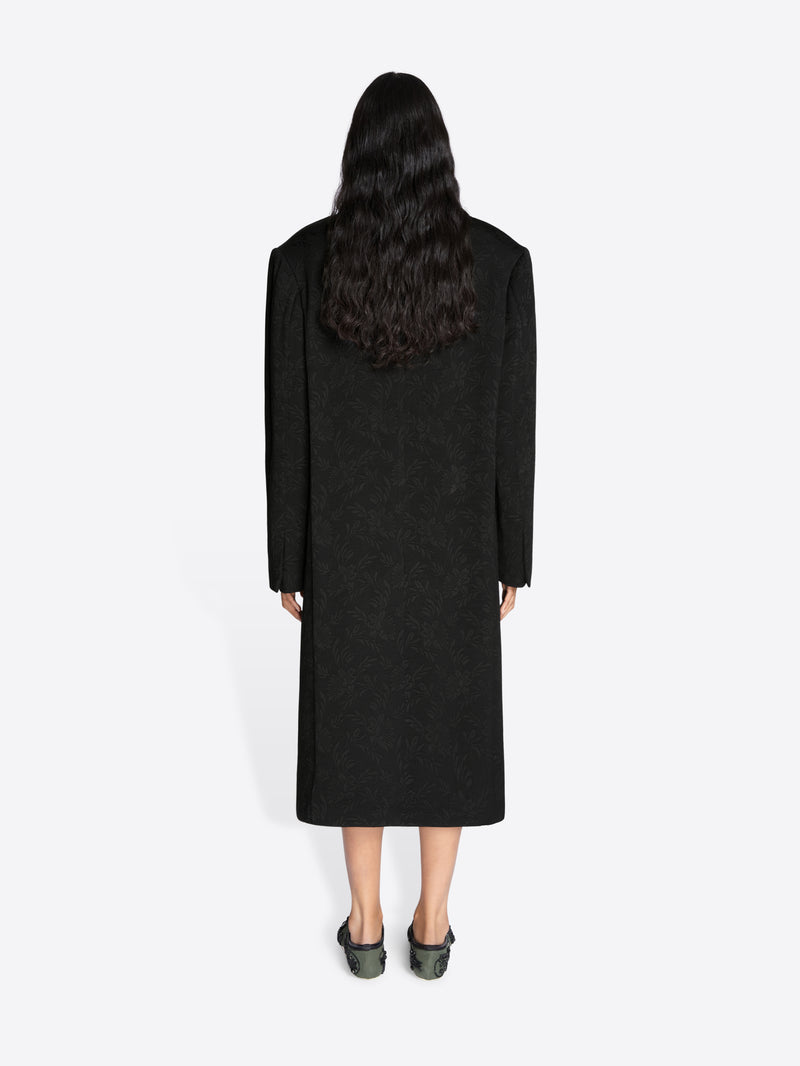 Person wearing a long black coat on a white background - Dries Van Noten