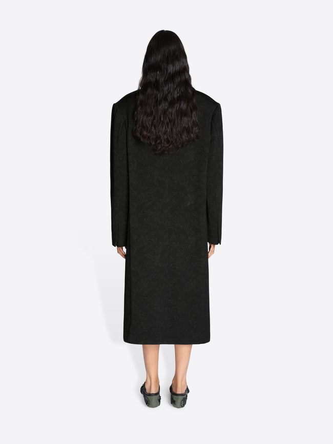 Person wearing a long black coat on a white background - Dries Van Noten