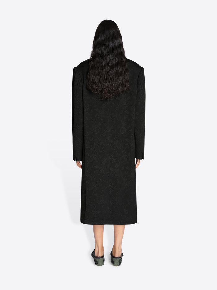 Person wearing a long black coat on a white background - Dries Van Noten