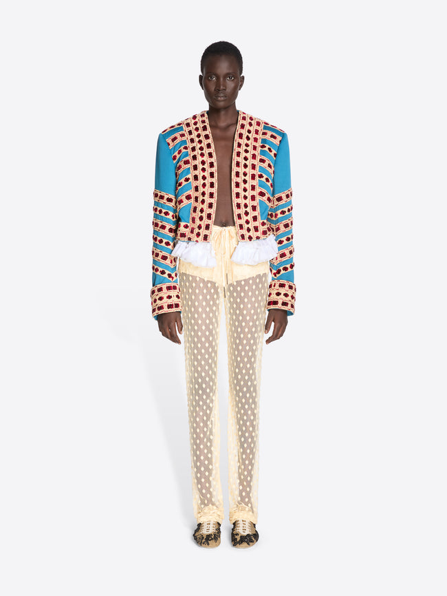 Person wearing a colorful patterned jacket and beige pants on a white background - Dries Van Noten