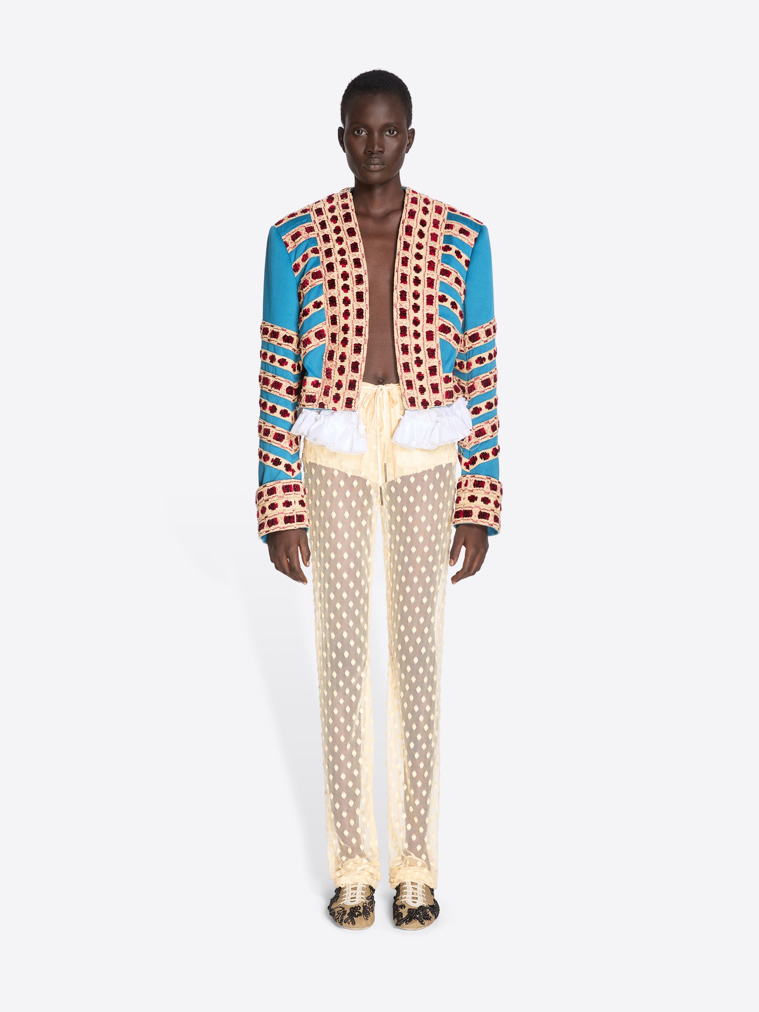Person wearing a colorful patterned jacket and beige pants on a white background - Dries Van Noten