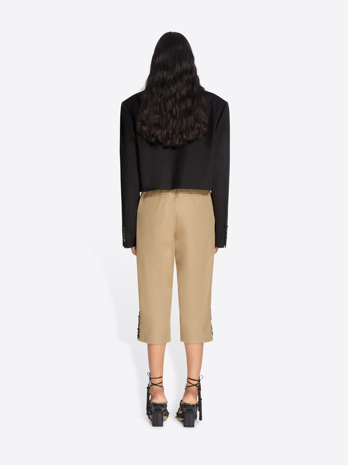 Person wearing a black top and beige pants on a white background - Dries Van Noten