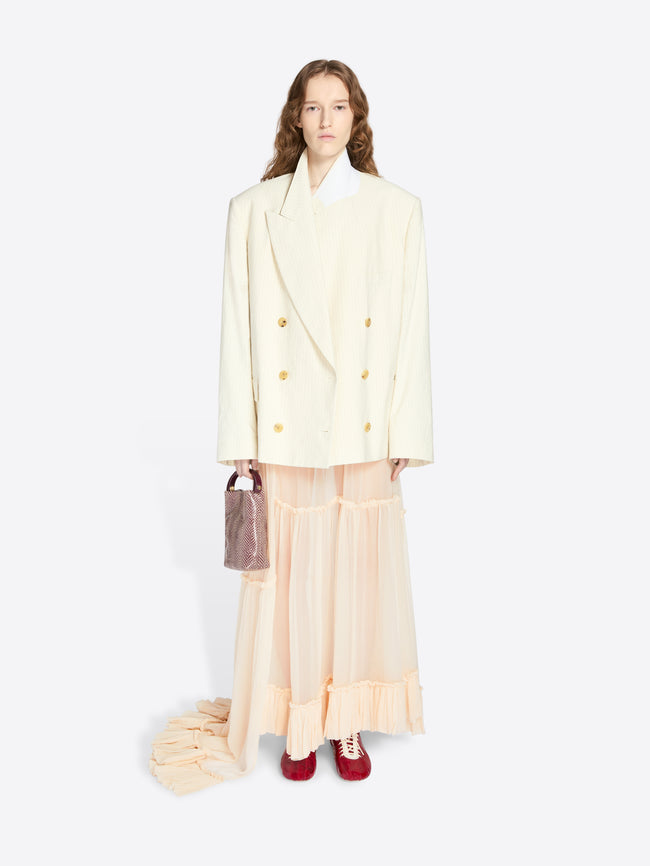 Woman wearing a light-colored coat with a sheer skirt on a white background - Dries Van Noten