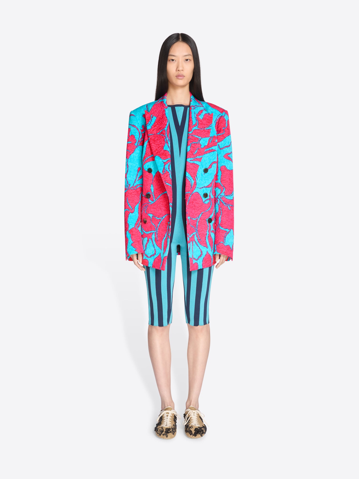 Person wearing a colorful jacket and striped jumpsuit on a white background - Dries Van Noten