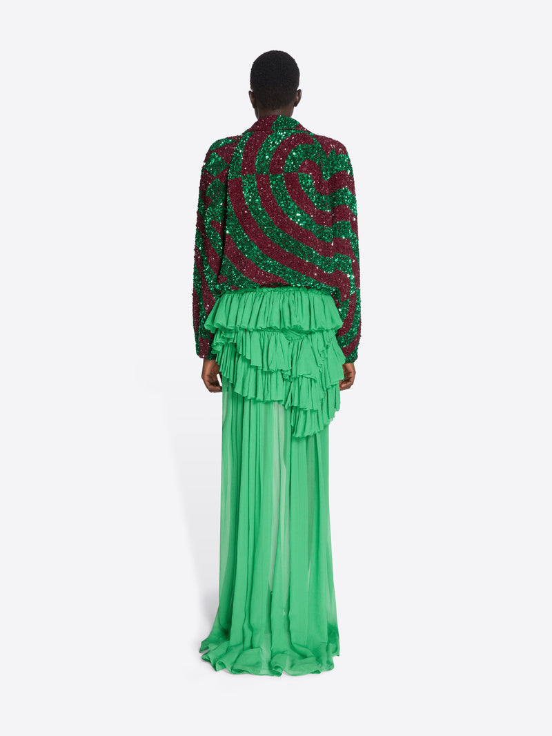 Person wearing a green and red patterned top with ruffled green skirt on a white background - Dries Van Noten