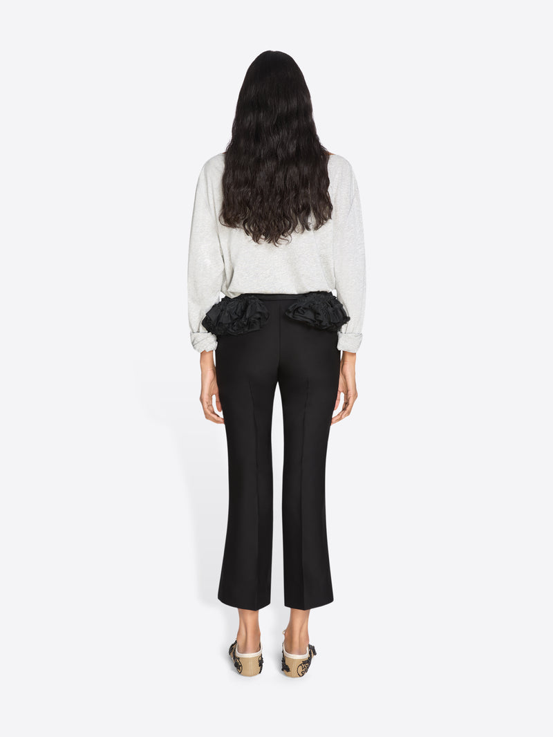 Woman wearing a white blouse with ruffled details and black pants on a white background - Dries Van Noten