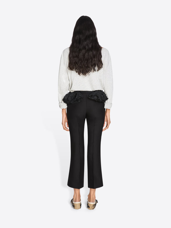 Woman wearing a white blouse with ruffled details and black pants on a white background - Dries Van Noten