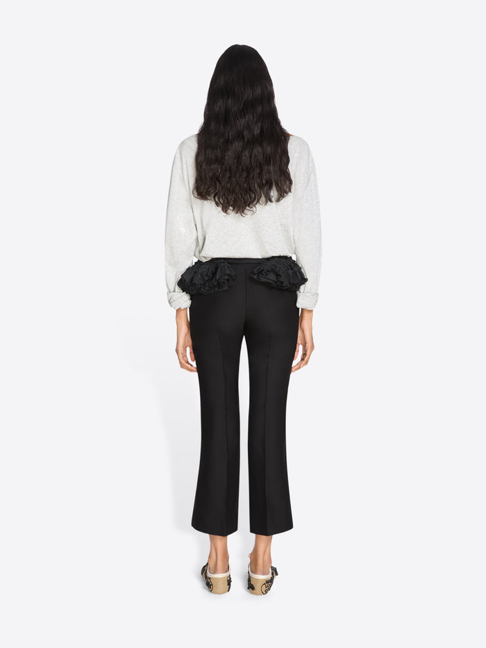 Woman wearing a white blouse with ruffled details and black pants on a white background - Dries Van Noten