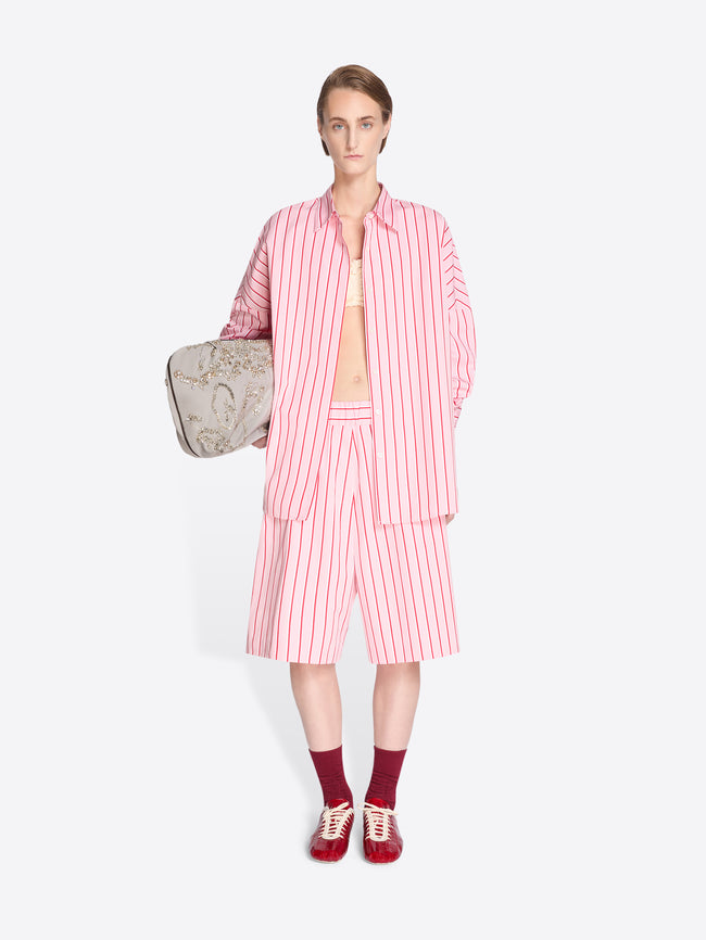 Woman wearing a pink and white striped outfit with a beige bag on a white background - Dries Van Noten