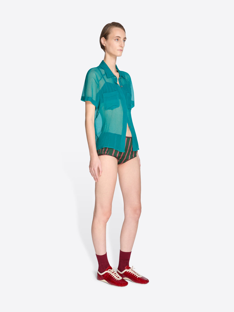 Woman wearing a green sheer top and red sneakers on a white background - Dries Van Noten
