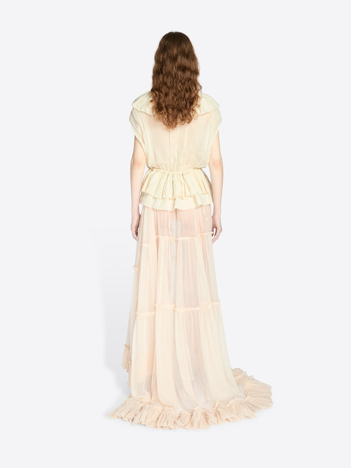 Woman wearing a long, light-colored dress with ruffled layers on a white background - Dries Van Noten