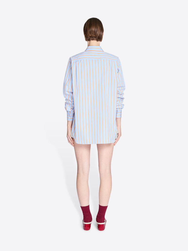 Person wearing a light blue striped shirt on a white background - Dries Van Noten