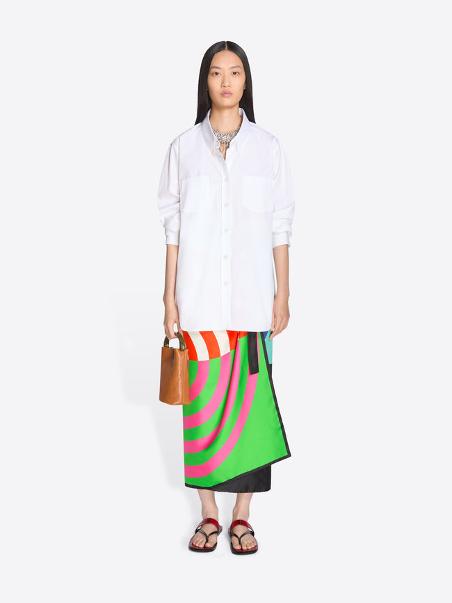 Woman wearing a white shirt and colorful skirt with a brown bag on a white background - Dries Van Noten