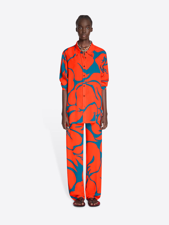Person wearing a vibrant orange and blue patterned outfit on a white background - Dries Van Noten