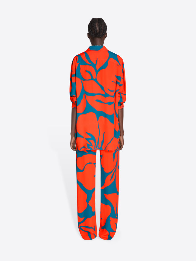 Person wearing a bright orange and blue patterned outfit on a white background - Dries Van Noten